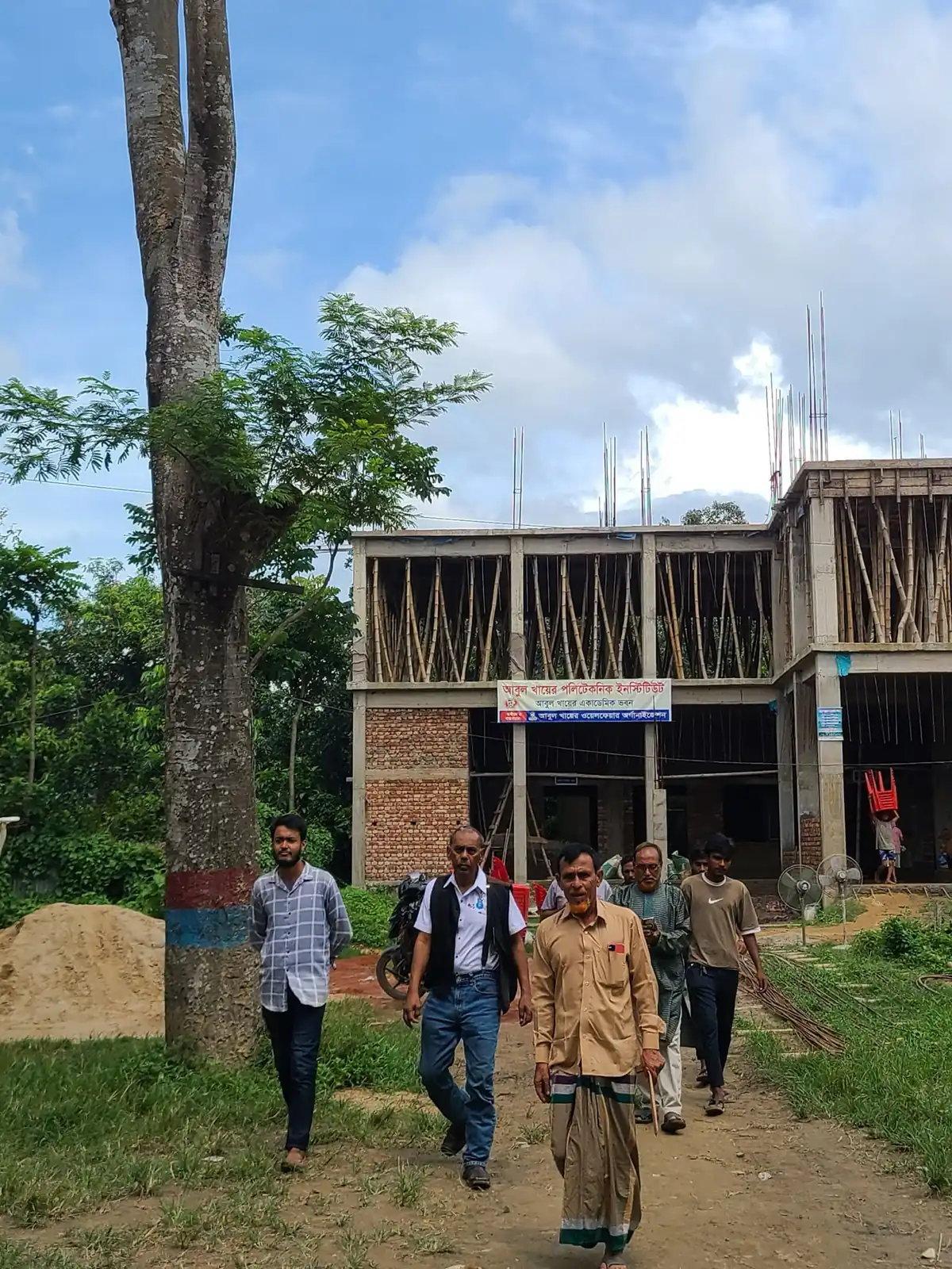 Team members walk towards the Abul Khair Academic Building site during construction