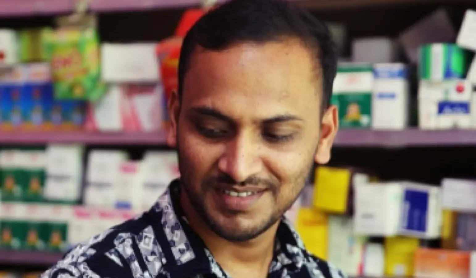 Anhar behind the counter of the pharmacy he opened with a small grant from AKWO