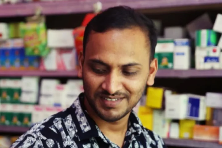 Anhar behind the counter of the pharmacy he opened with a small grant from AKWO