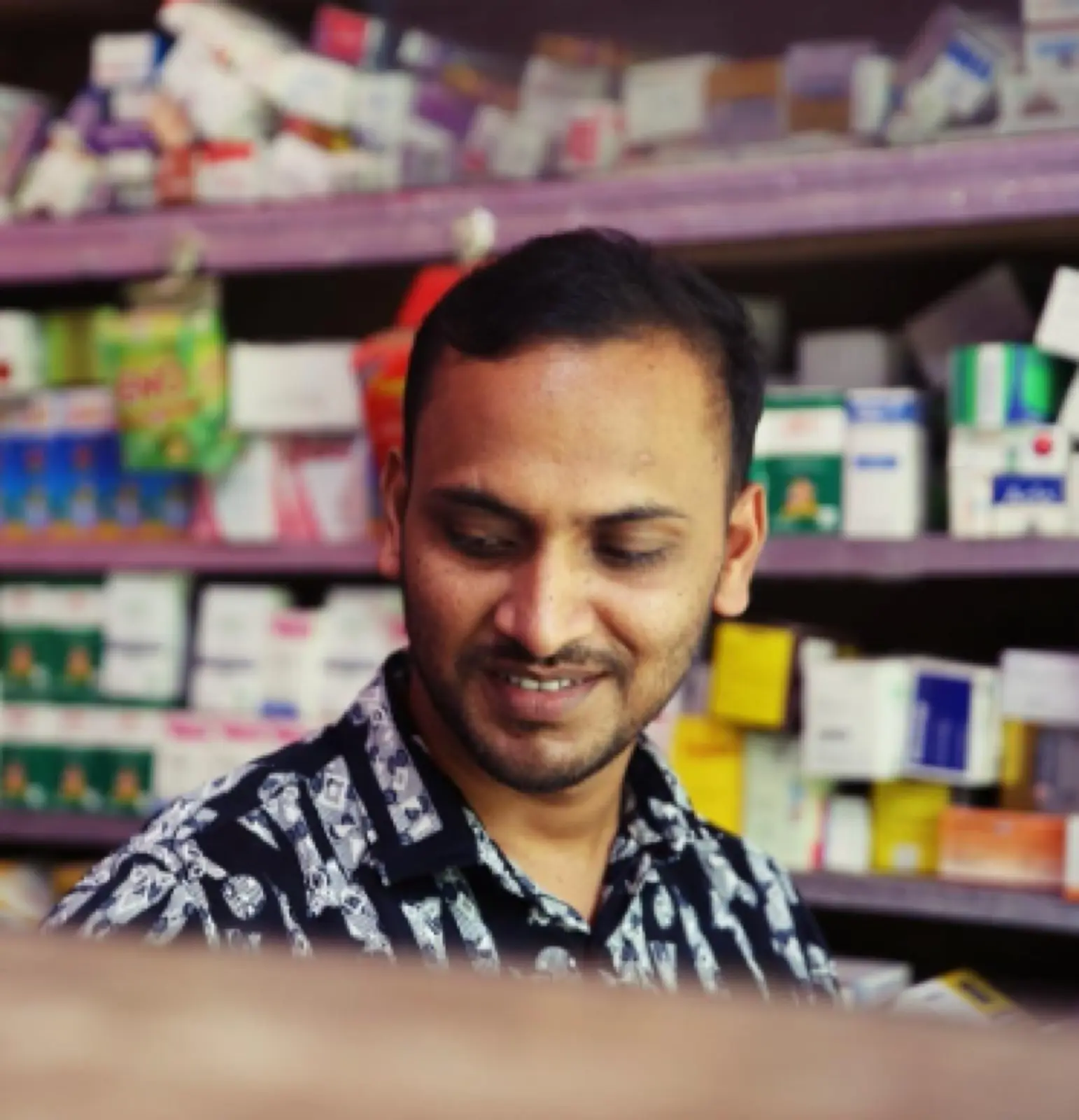 Anhar behind the counter of the pharmacy he opened with a small grant from AKWO