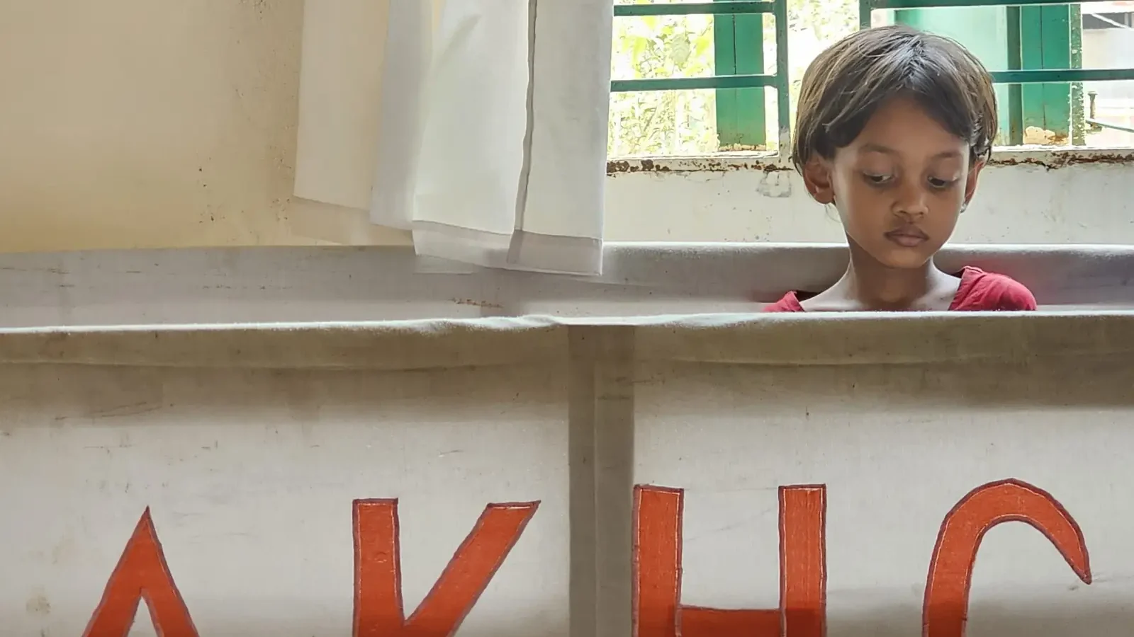 A child looks over the counter marked AKHC at the Baishmouja clinic