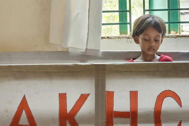 A child looks over the counter marked AKHC at the Baishmouja clinic