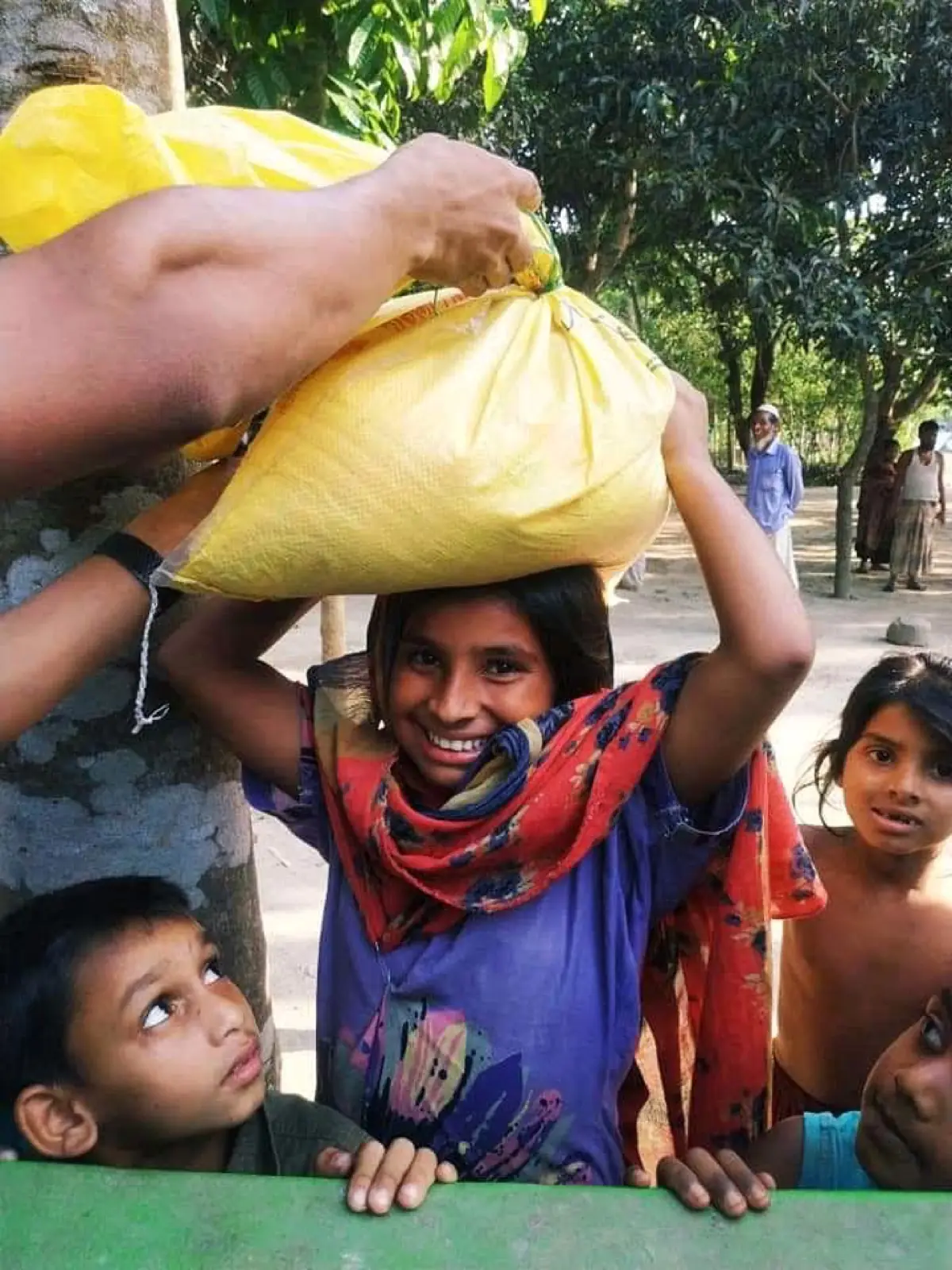 A child carries a sack of food relief on her head during the 2020 COVID-19 distribution