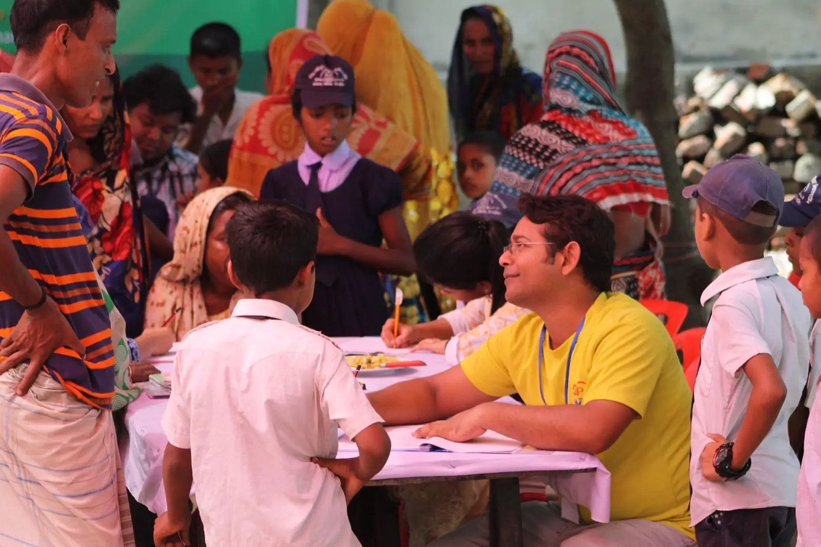 Children crowd around the registration table at a village health camp in 2019