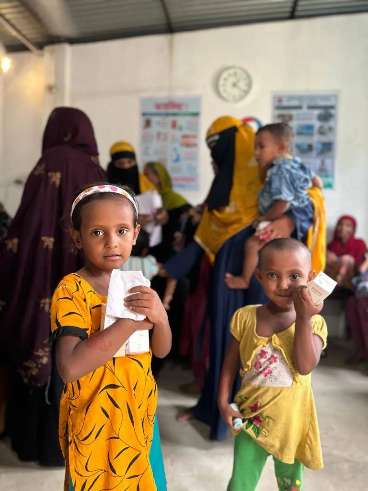 Two young girls hold food packets received at an AKWO distribution