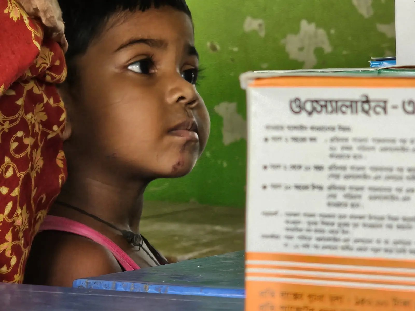 A young girl waits beside the medicine table at the free Friday clinic in Baishmouja, September 2024
