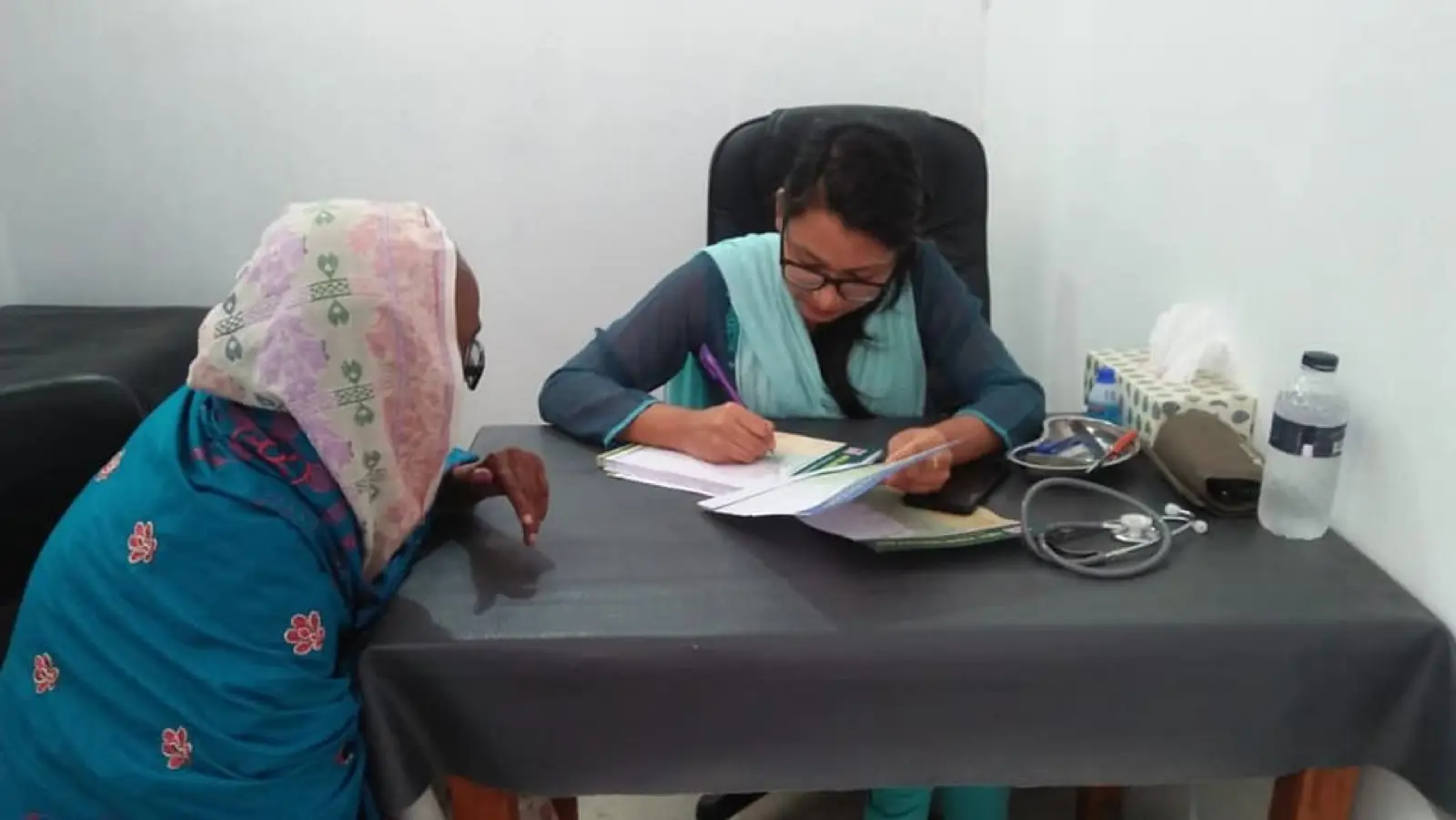 A clinic assistant takes a patient's blood pressure and details at the AKHC office
