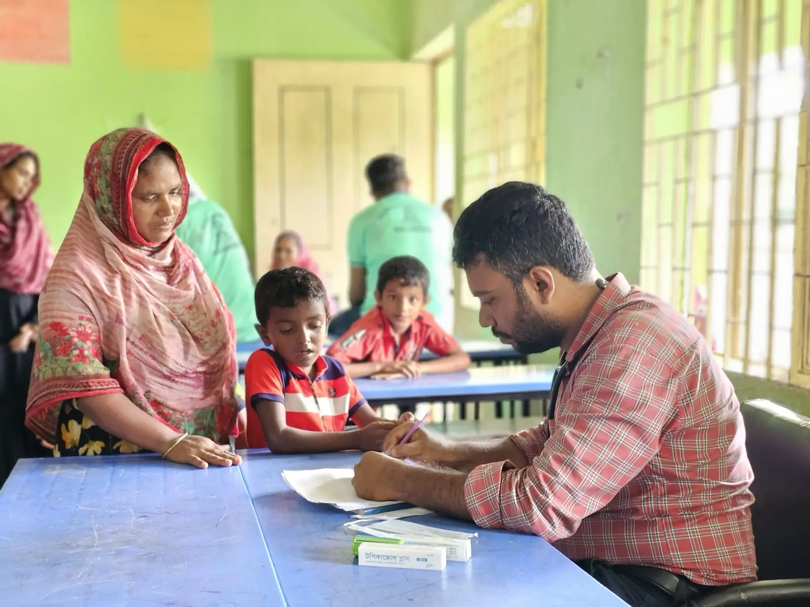 A health worker registers a mother and her son at the Friday clinic in Baishmouja