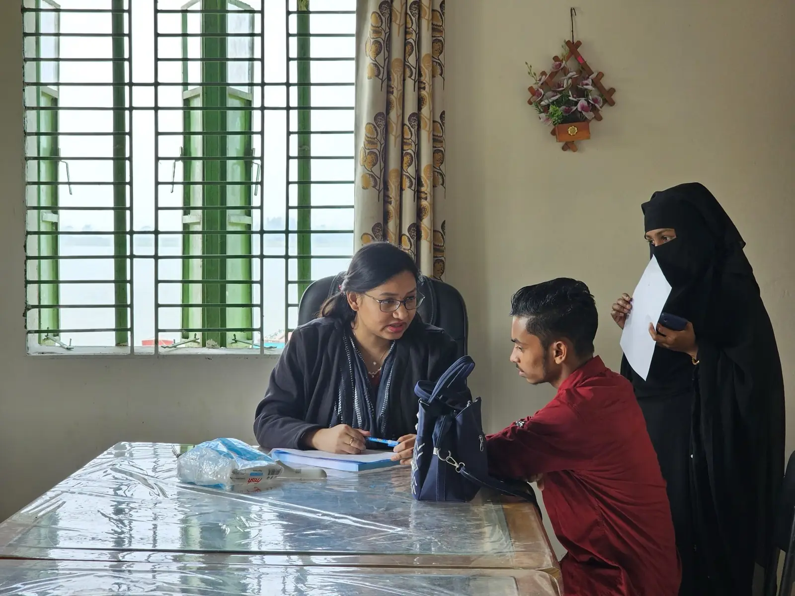 A doctor and a clinic assistant consult a patient at the AKWO office in Baishmouja, January 2025