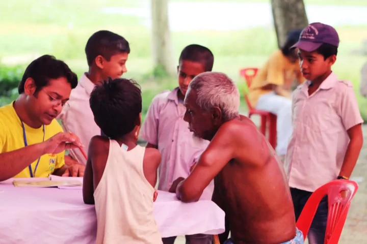 A volunteer registers children and an elderly man at one of AKWO's first health camps in 2019