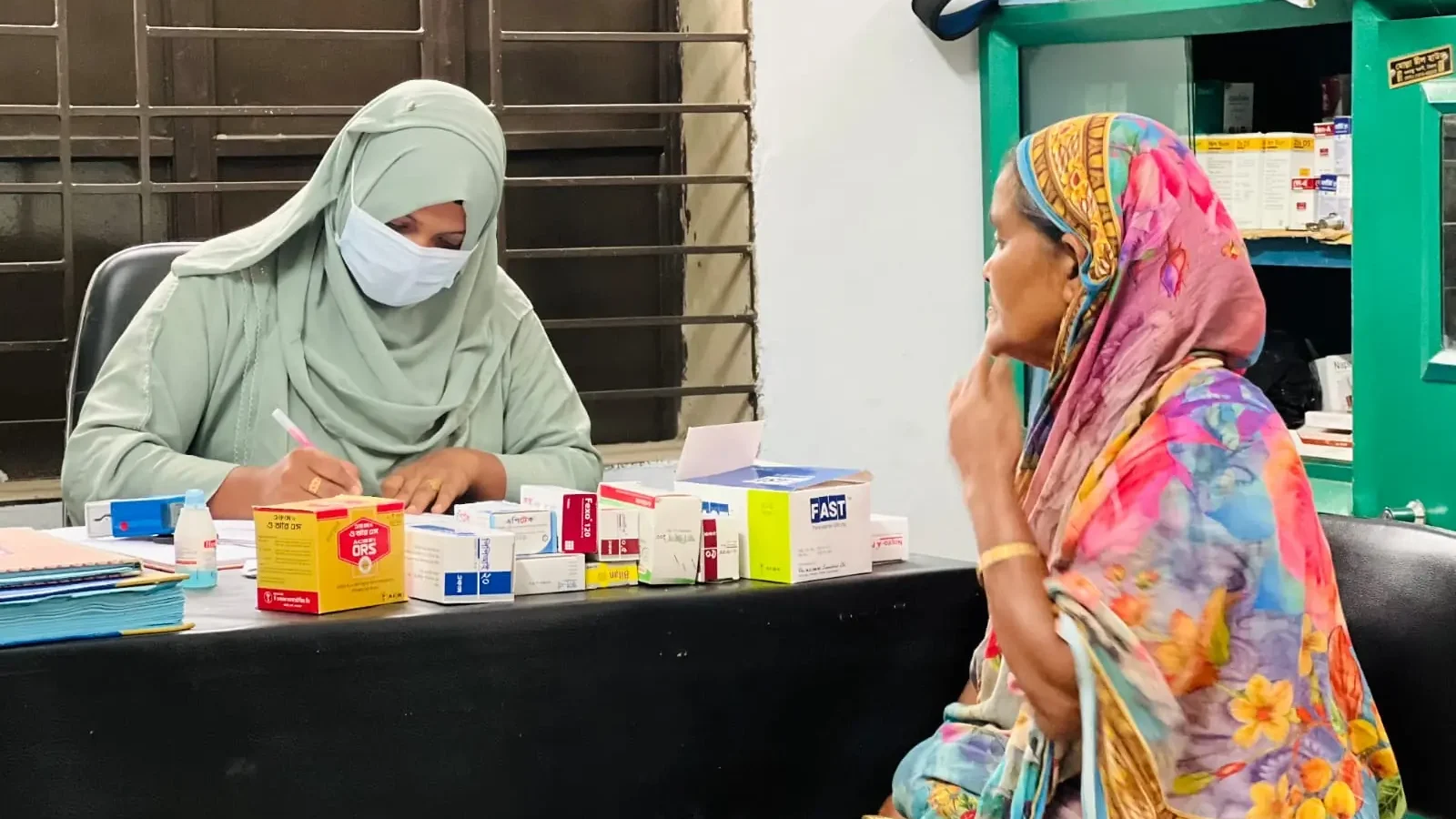 A clinic assistant hands medicine to a woman at the free medical camp on 1 May 2026
