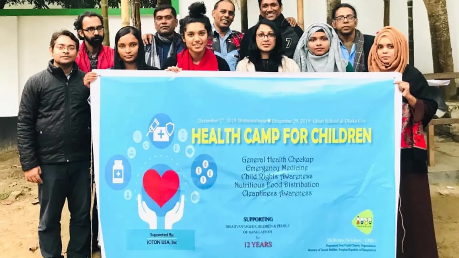 Volunteers hold the Health Camp for Children banner at the start of a camp in 2020