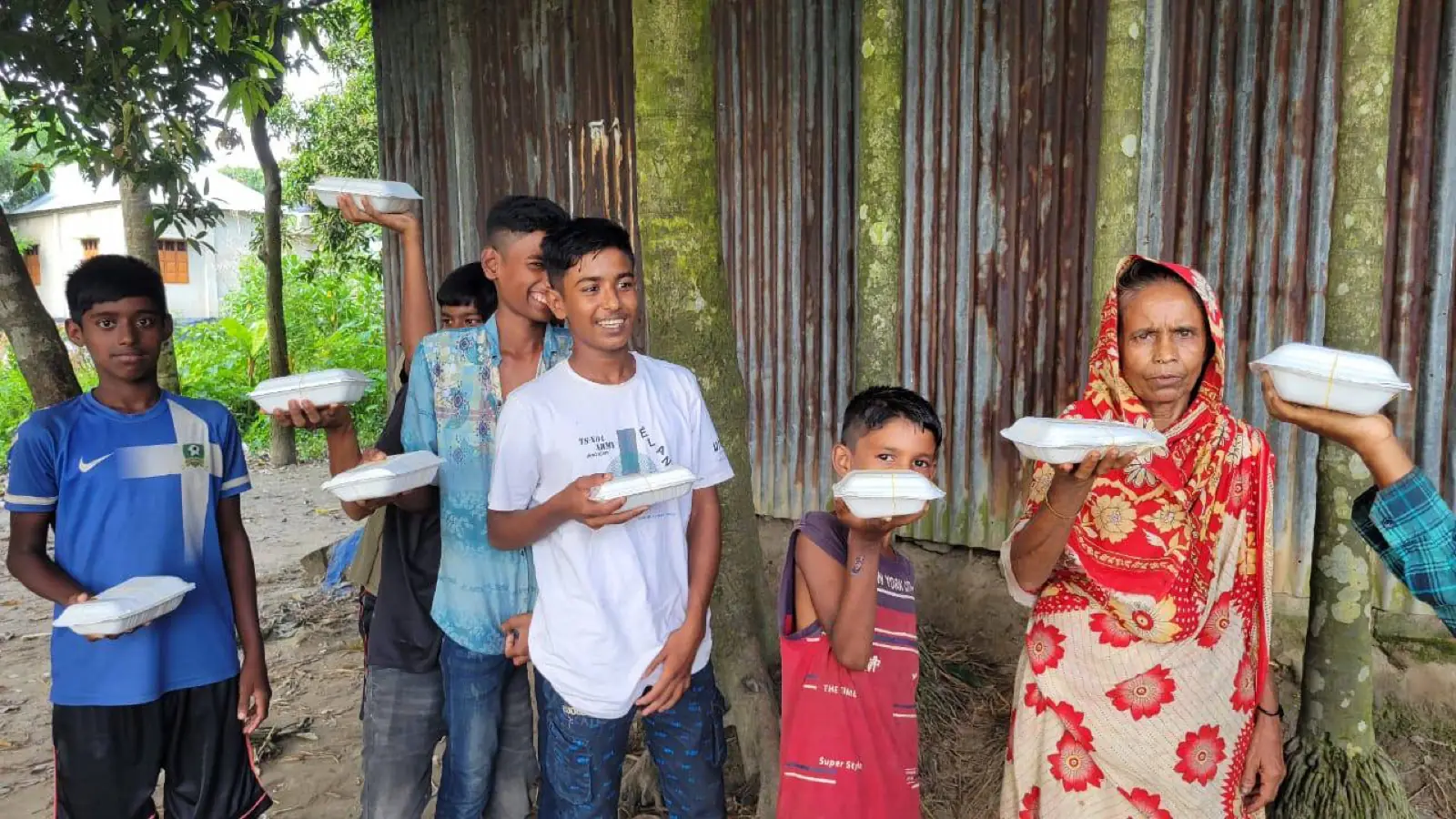 Young people hold hot meal boxes received at an AKWO food distribution