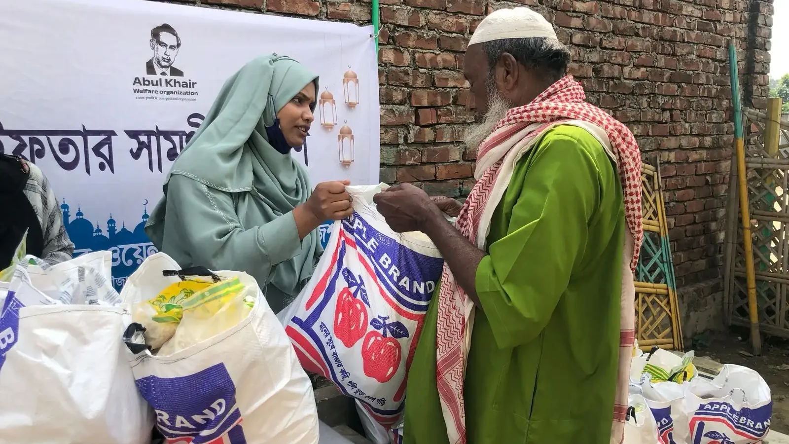 A volunteer hands an Iftar package of rice and staples to an elderly man during Ramadan