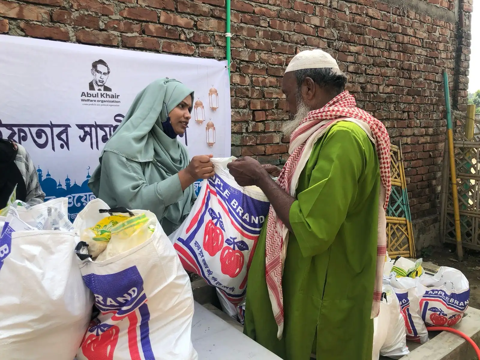 A volunteer hands an Iftar package of rice and staples to an elderly man during Ramadan