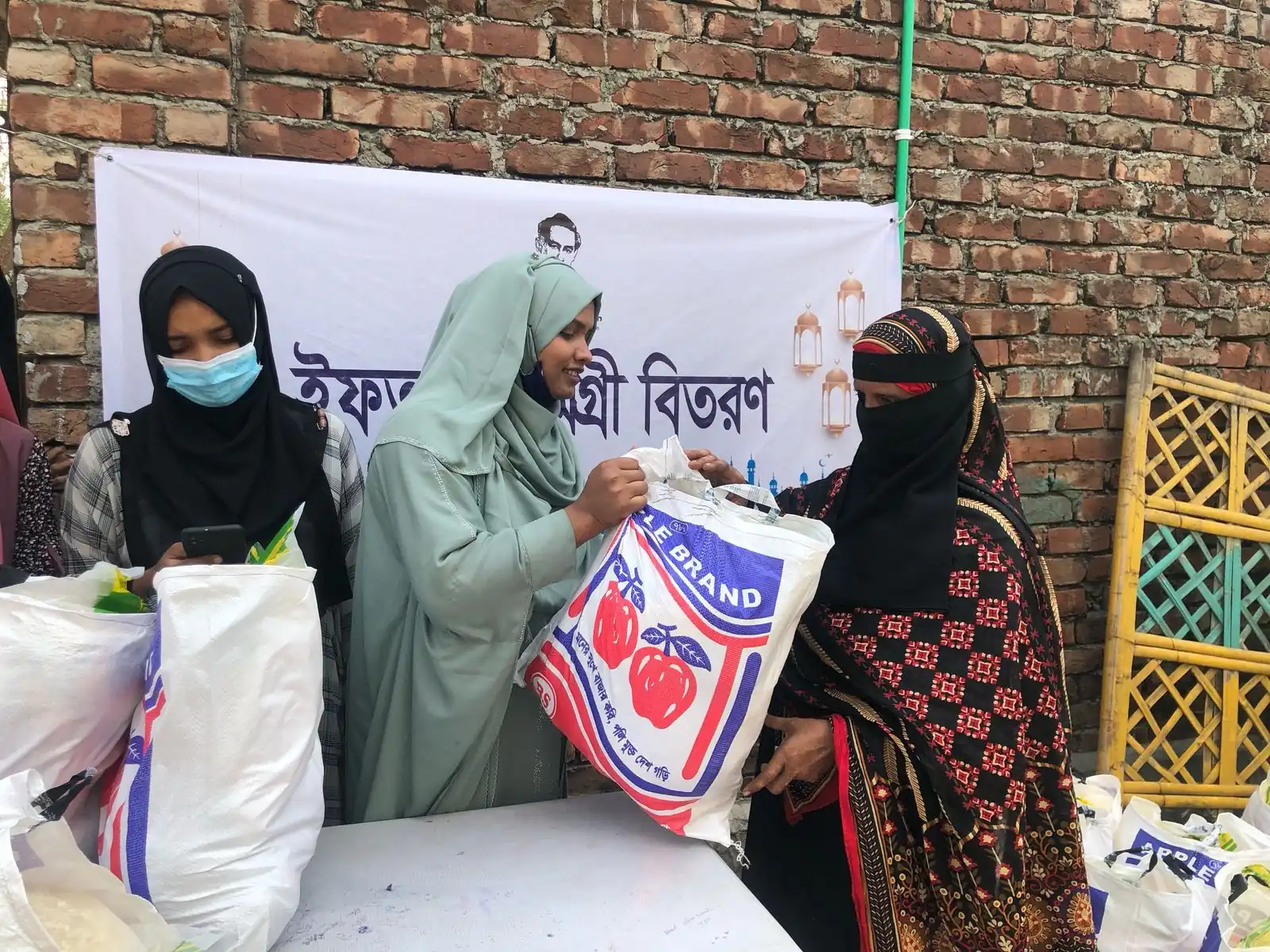 Volunteers hand Iftar packages to women at the AKWO distribution point