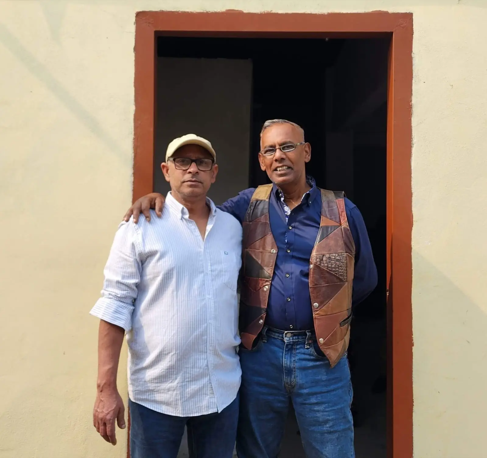 Marshall M. Hussain stands with a neighbor in the doorway of a village home in Nabinagar