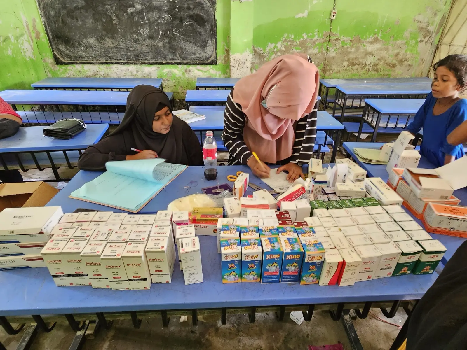 Volunteers sort packets of free medicine on the dispensing table at the Baishmouja clinic