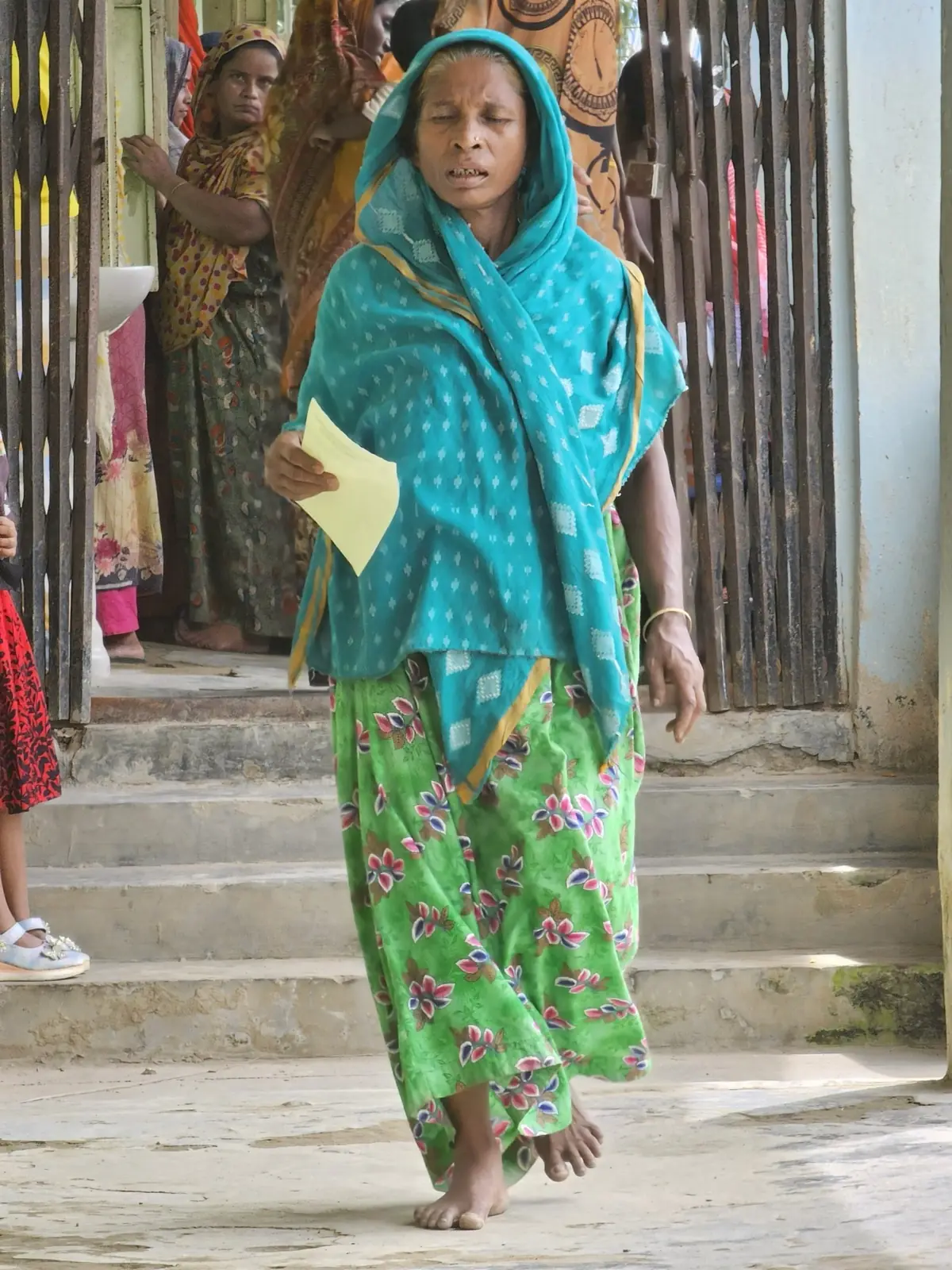A woman walks down the clinic steps holding the prescription she has just been given