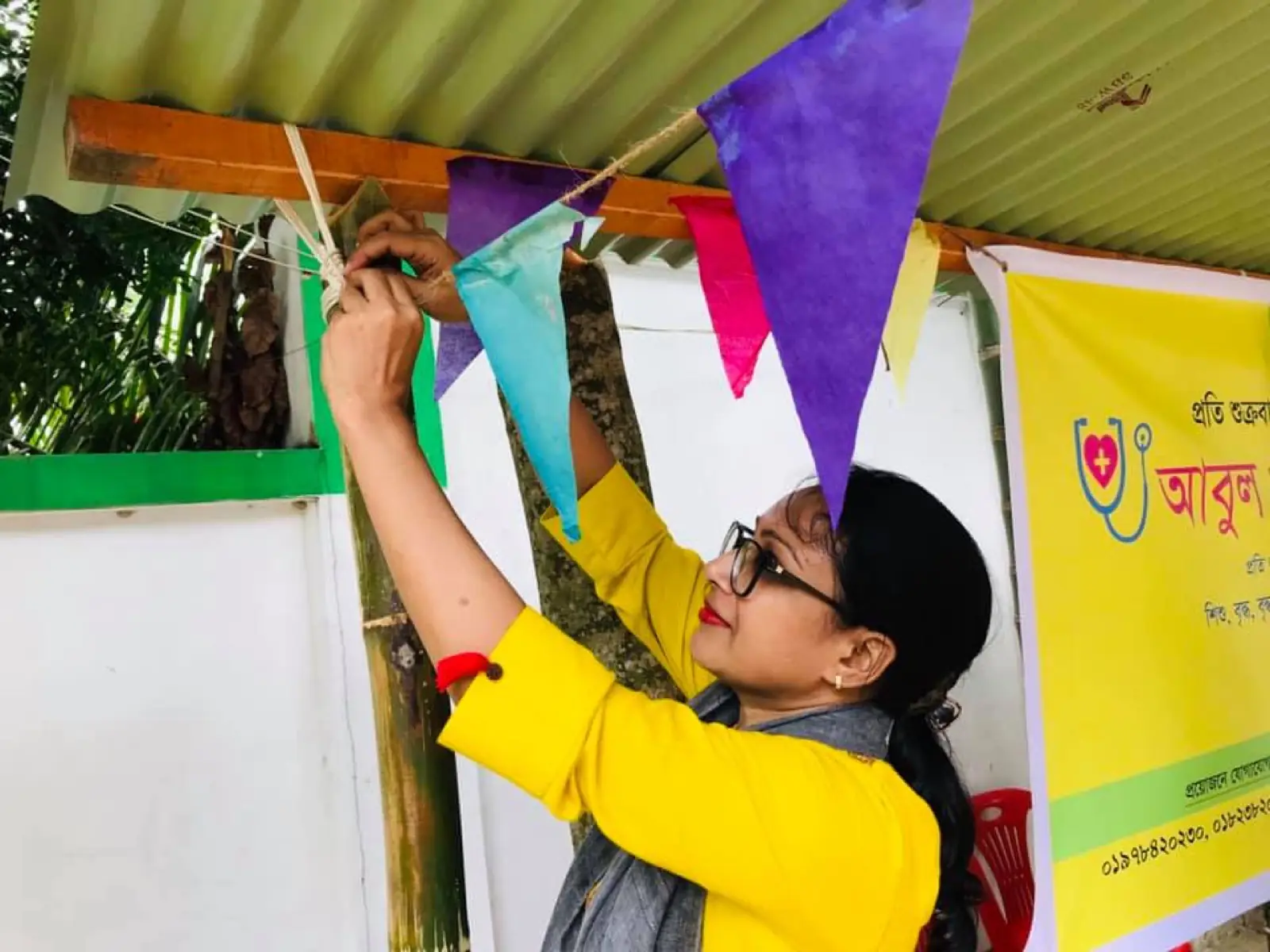 A volunteer hangs bunting and the AKWO banner before a health camp opens